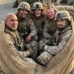 Goldberg, The Rock, John Cena, Brock Lesnar, and Roman Reigns enjoy recreational activities at a military base.